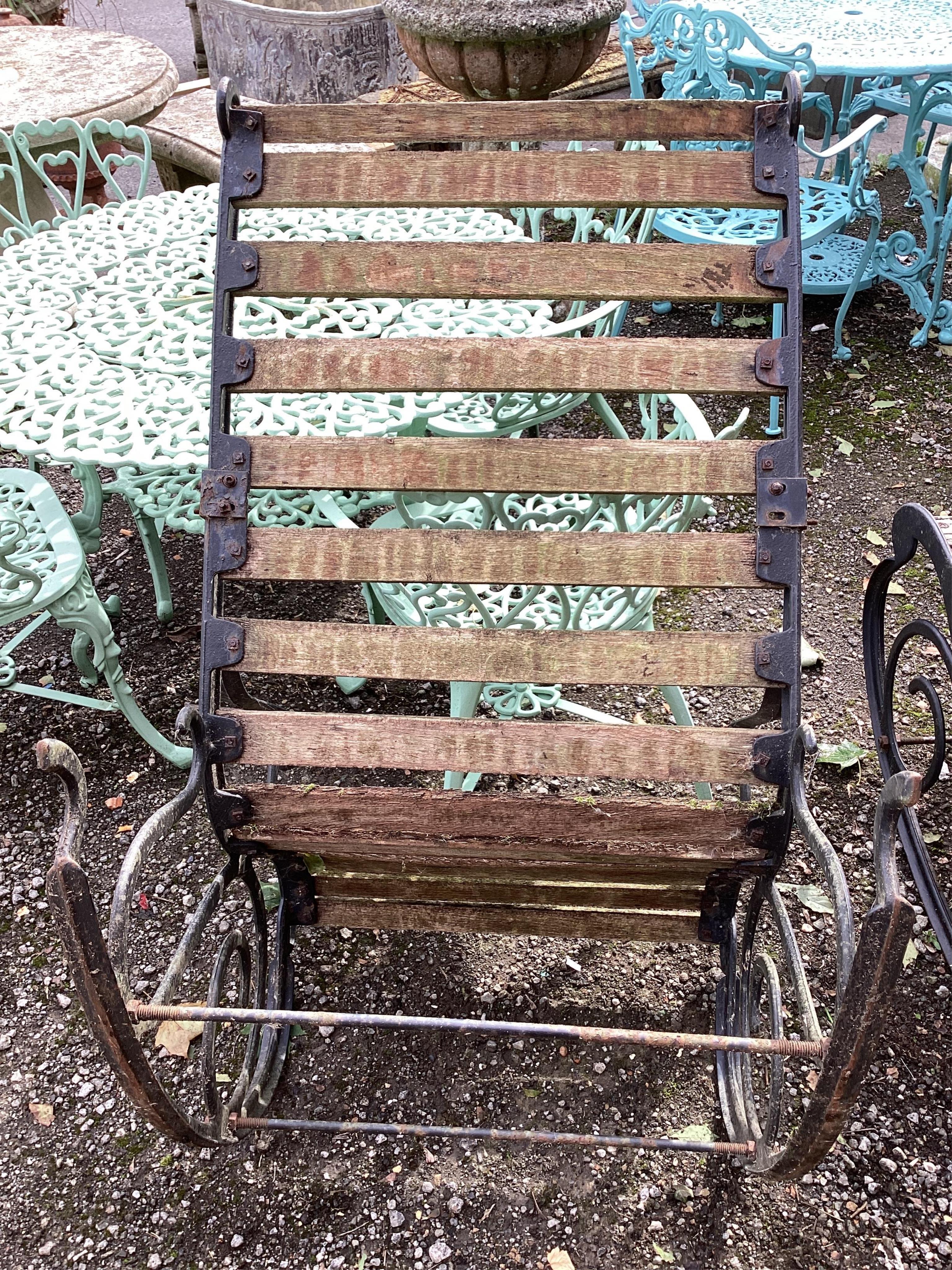 A pair of slatted cast metal garden rocking chairs